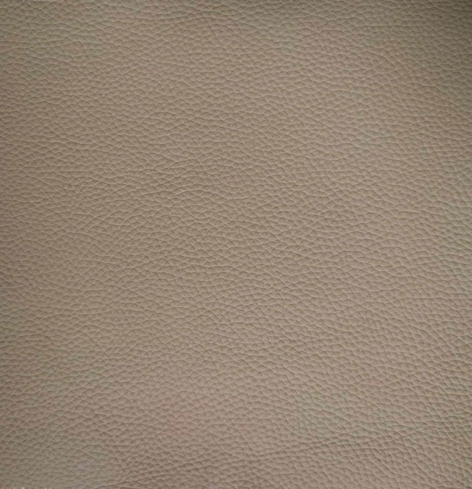 Nahaufnahme einer beige strukturierten Lederoberfläche, die für einen Armlehnstuhl verwendet wird.