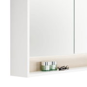 Nahaufnahme eines weißen Spiegelschranks mit zwei Glastiegeln und einer Brille auf einem Regalbrett, seitliche Perspektive