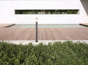 Moderne Außenleuchte BOSTON auf einer Holzterrasse mit Blick auf einen Pool und eine grüne Hecke im Hintergrund.