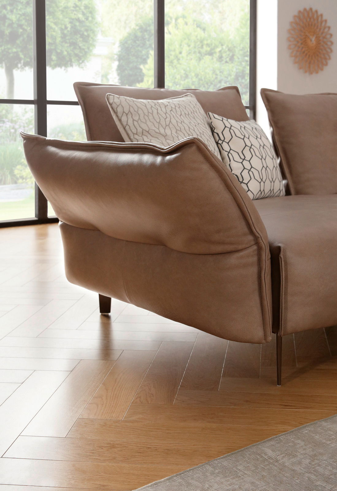 Nahaufnahme einer eleganten, braunen Polsterrundecke mit modernen Kissen, seitliche Perspektive.