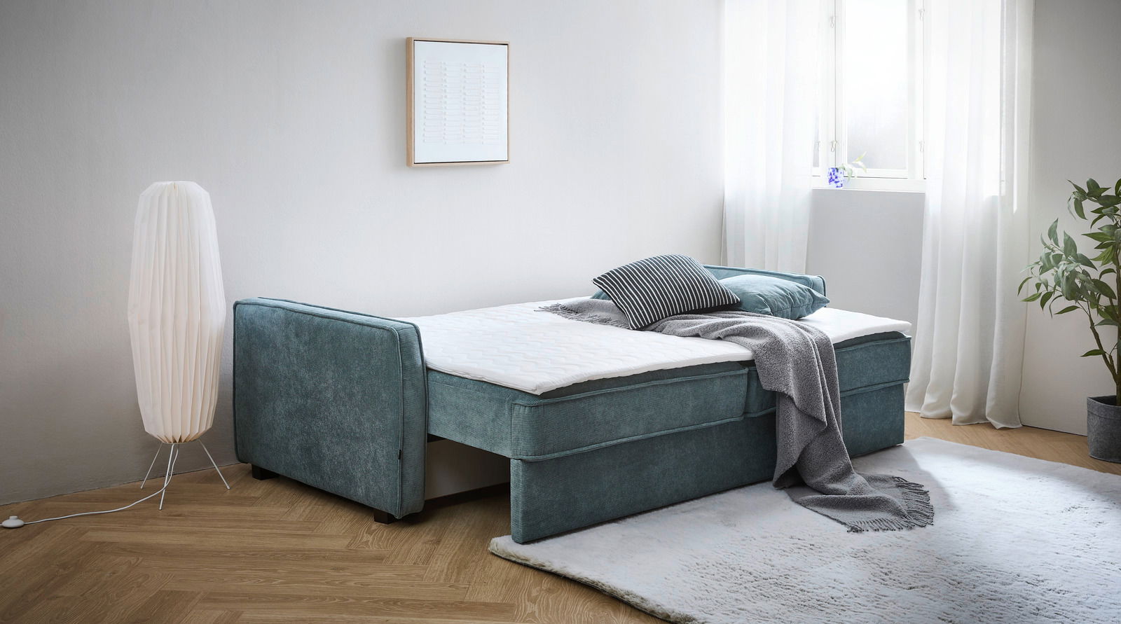 Funktionssofa in einem modernen Wohnzimmer, seitliche Perspektive, mit Kissen und Decke dekoriert.