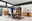 Zurbrüggen LED Rückwand Beleuchtung AREZZO Modernes Wohnzimmer mit Holzmöbeln, darunter ein Highboard, Sideboard und Vitrine, aus hellem Holz mit LED-Beleuchtung, umgeben von großen Fenstern. Perspektive: Frontalansicht.