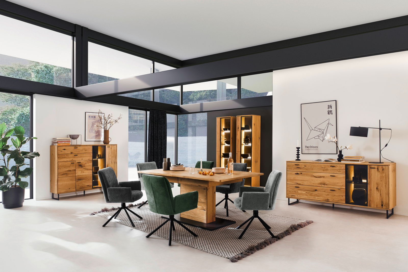 Modernes Wohnzimmer mit Holzmöbeln, darunter ein Highboard, Sideboard und Vitrine, aus hellem Holz mit LED-Beleuchtung, umgeben von großen Fenstern. Perspektive: Frontalansicht.