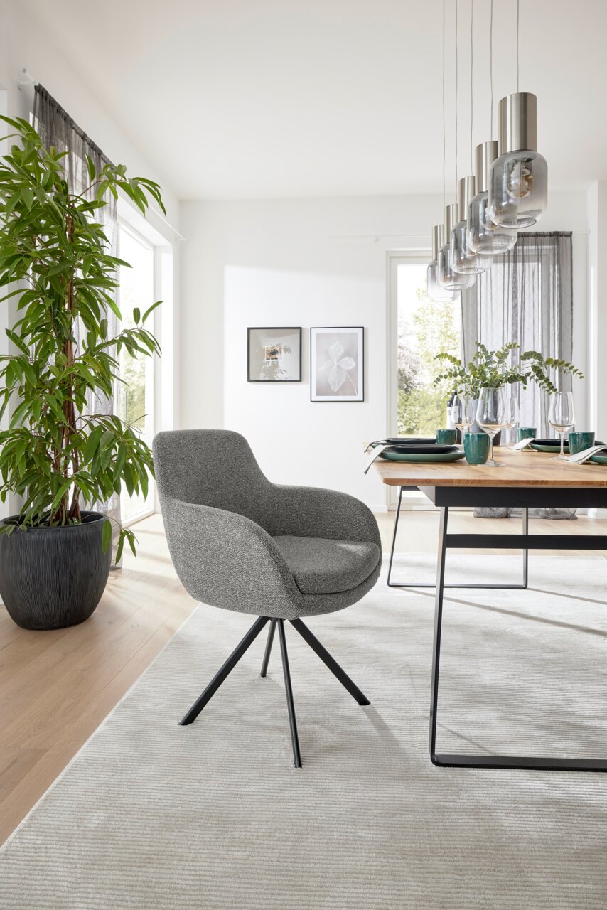 Grauer Armlehnstuhl mit schwarzem Metallgestell in modernem Esszimmer, seitliche Perspektive