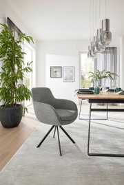 Grauer Armlehnstuhl mit schwarzem Metallgestell in modernem Esszimmer, seitliche Perspektive
