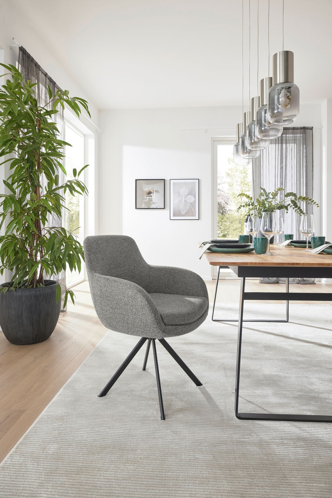 Grauer Armlehnstuhl mit schwarzem Metallgestell in modernem Esszimmer, seitliche Perspektive