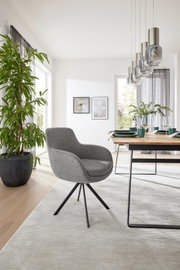 Grijze fauteuil met zwart metalen frame in een moderne eetkamer, zijaanzicht