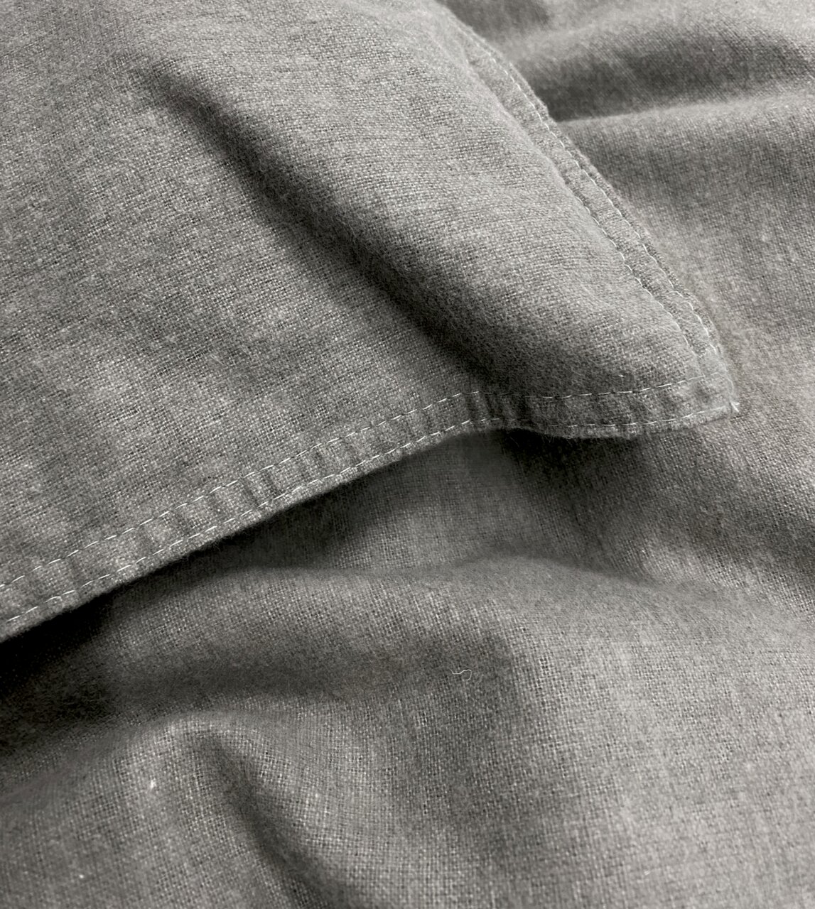Nahaufnahme von grauer, stone-washed Bettwäsche mit sichtbaren Nähten und weicher Textur.
