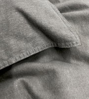Nahaufnahme von grauer, stone-washed Bettwäsche mit sichtbaren Nähten und weicher Textur.