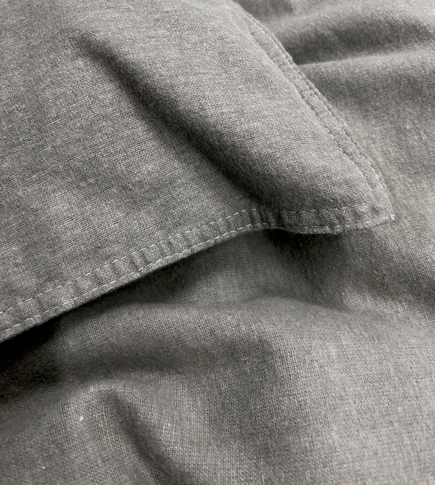 Nahaufnahme von grauer, stone-washed Bettwäsche mit sichtbaren Nähten und weicher Textur.