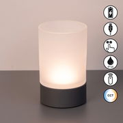 Zylindrisches Akku-Windlicht mit mattem Glas und dunklem Sockel, frontal fotografiert. Symbole für USB-Ladung, Touch-Bedienung, IP54-Schutz, Fernbedienung und CCT-Farbtemperaturwechsel sind sichtbar.