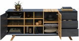 Modernes Sideboard mit offenen Türen und Schubladen, gefüllt mit Büchern, Geschirr und Dekorationen, aus dunklem Holz und Metall, frontal betrachtet.
