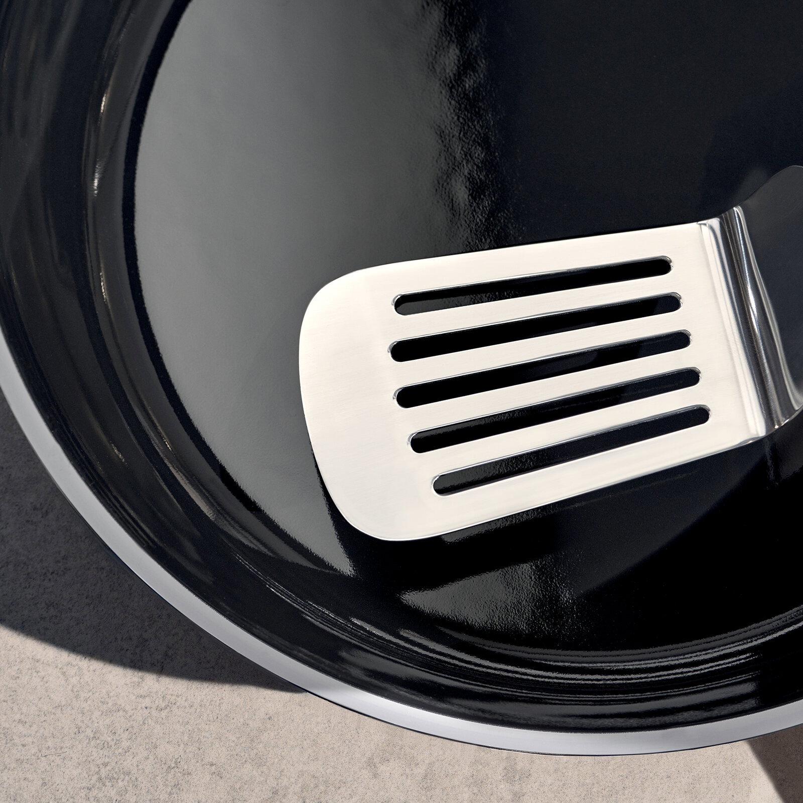 Nahaufnahme einer glänzenden schwarzen Pfanne mit einem silbernen Pfannenwender.