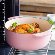 Runder Gusseisen Bräter in Rosa mit gebratenem Hähnchen und Gemüse, seitliche Perspektive im Ofen.