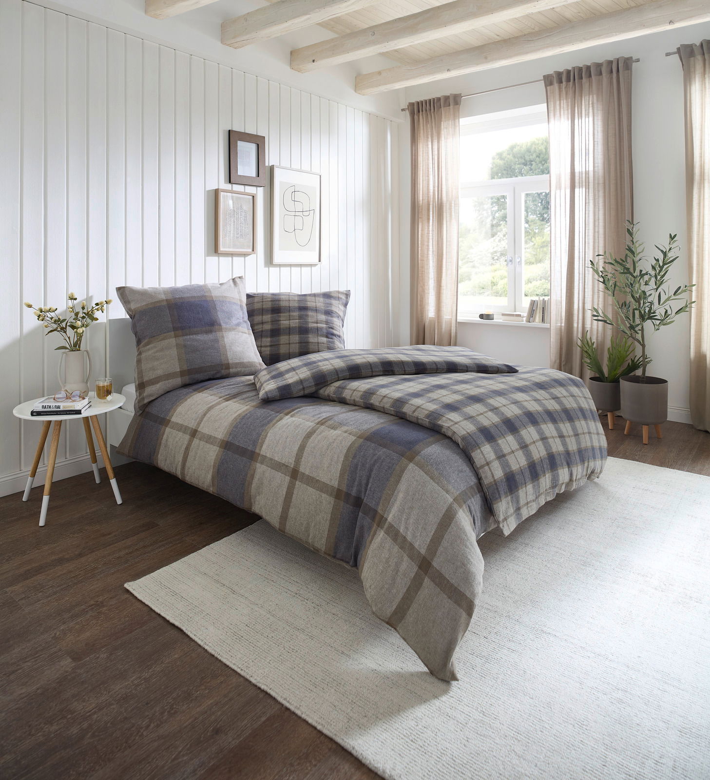 Gemütliches Schlafzimmer mit kariertem Bettwäsche-Set in Blau- und Beigetönen, seitliche Perspektive auf das Bett, helle und einladende Atmosphäre mit natürlichem Licht.