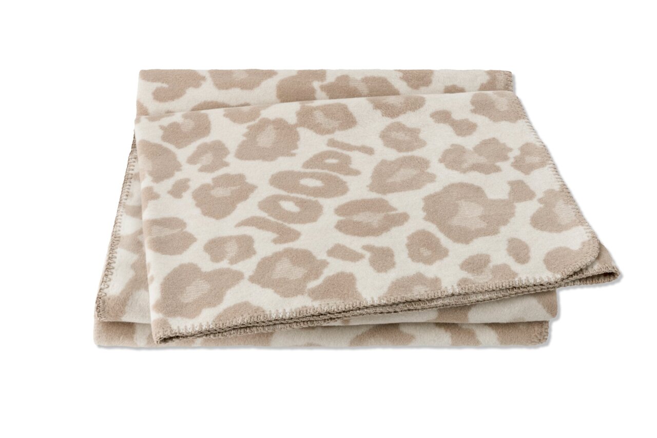 Gefaltete beige Wohndecke mit Leopardenmuster und dem Schriftzug 'JOOP!' in der Mitte, von oben fotografiert.