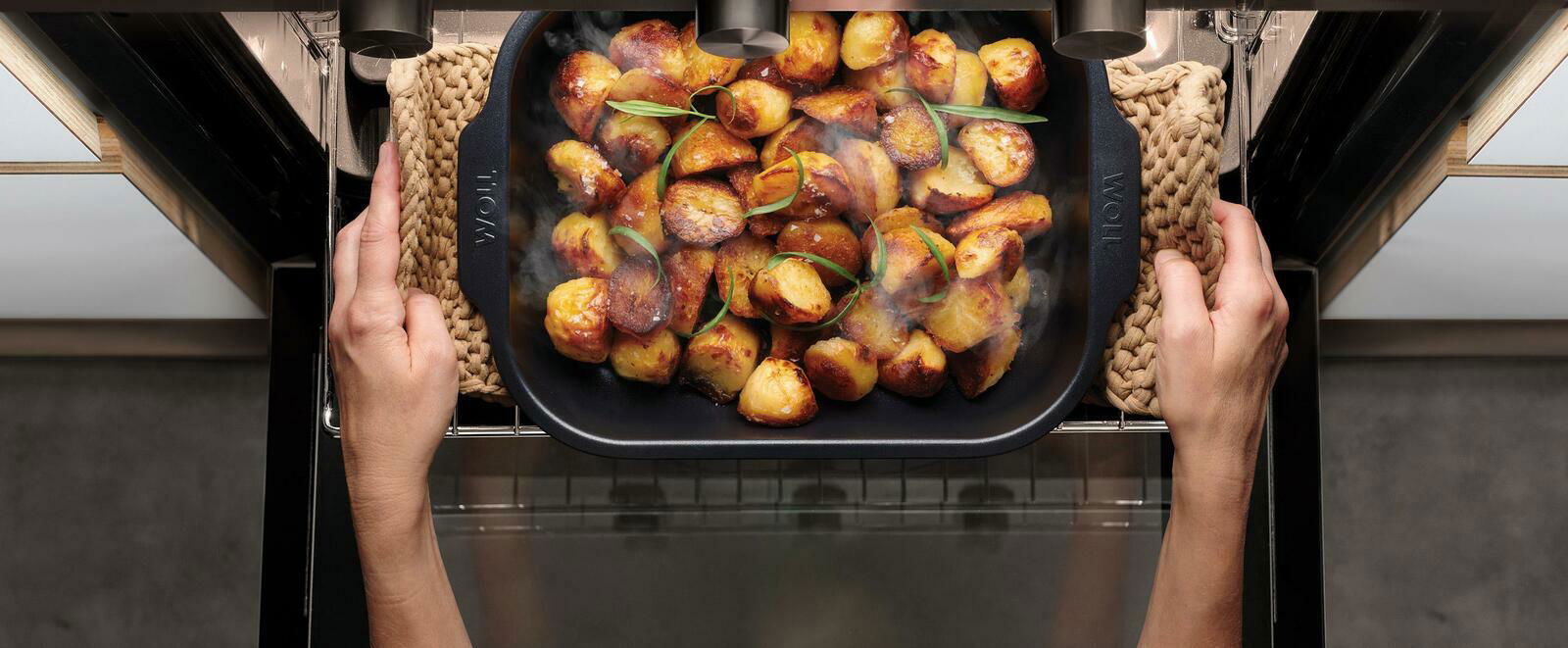 Woll Braadpan ROAST IT Bratreine mit goldbraun gerösteten Kartoffeln, aus der Vogelperspektive im Ofen gehalten.
