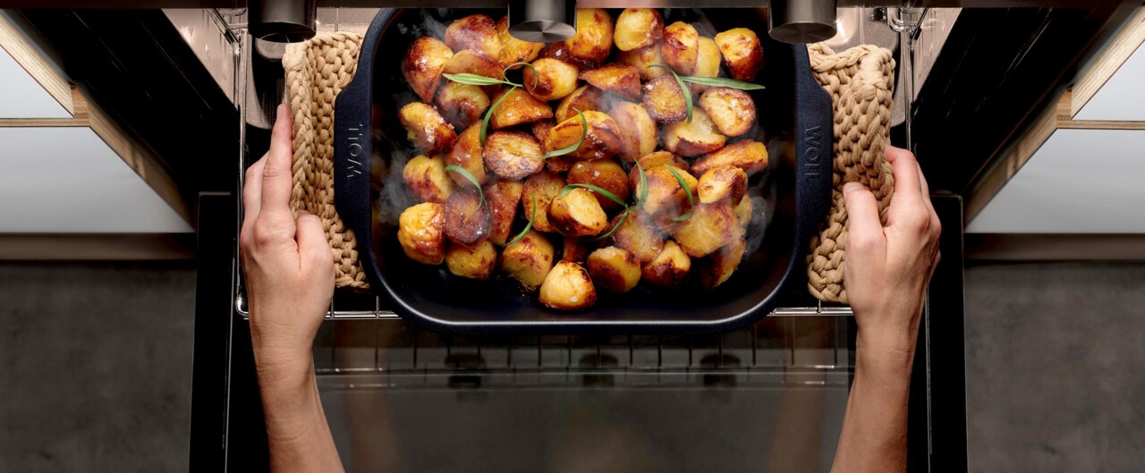 Woll Bratreine ROAST IT Bratreine mit goldbraun gerösteten Kartoffeln, aus der Vogelperspektive im Ofen gehalten.