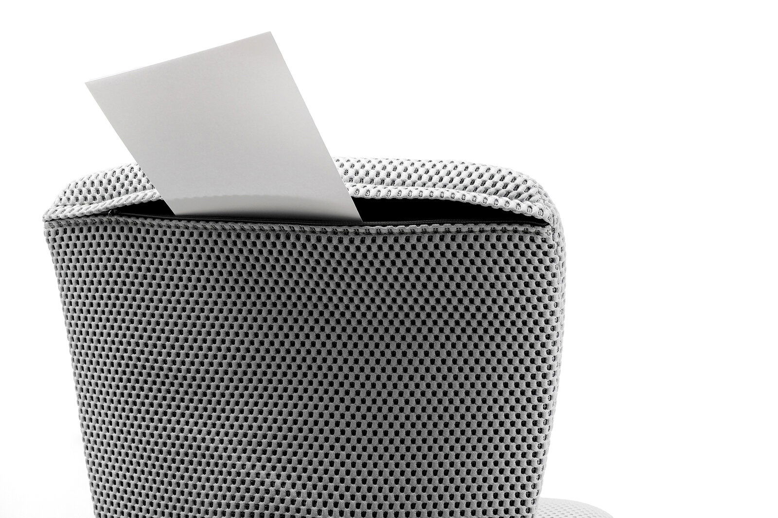 Rückansicht eines Kinder- und Jugenddrehstuhls mit grauem Netzbezug und einem weißen Blatt Papier, das aus der Rückenlehne herausragt.