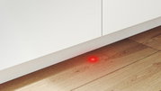 Rood lampje op de vloer voor een inbouwvaatwasser, gezien van voren.