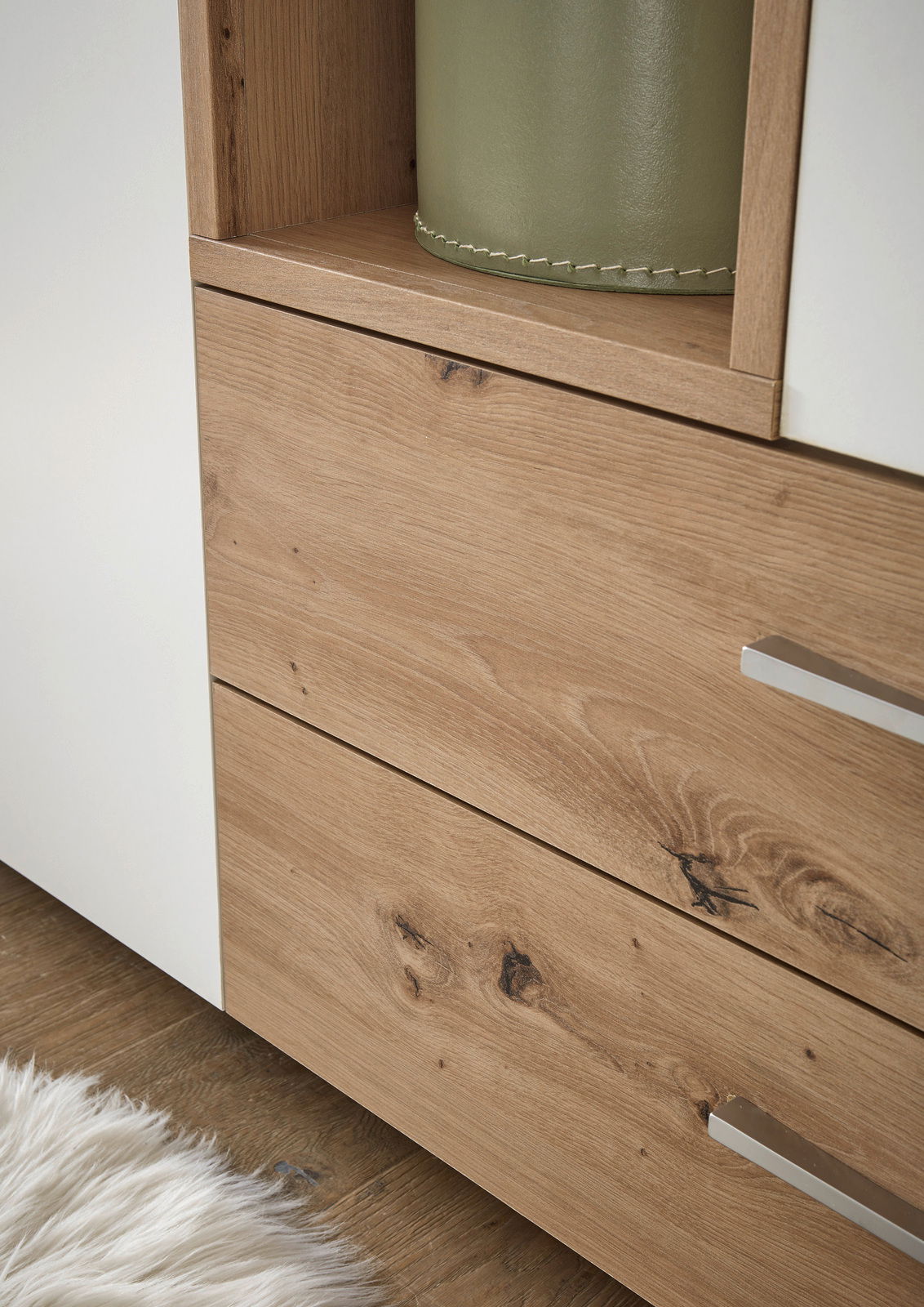 Nahaufnahme eines zweitürigen Drehtürenschranks mit Holzoptik und weißen Elementen, Perspektive von der Seite.