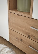 Nahaufnahme eines zweitürigen Drehtürenschranks mit Holzoptik und weißen Elementen, Perspektive von der Seite.