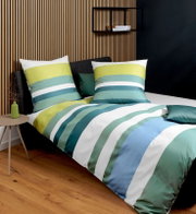 Gestreifte Bettwäsche in Grün-, Blau- und Weißtönen auf einem Bett mit dunklem Kopfteil, fotografiert in schräger Vorderansicht im modern eingerichteten Schlafzimmer