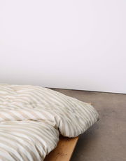 Bettwäsche mit beige-weißen Streifen auf einem Holzbett, seitliche Perspektive