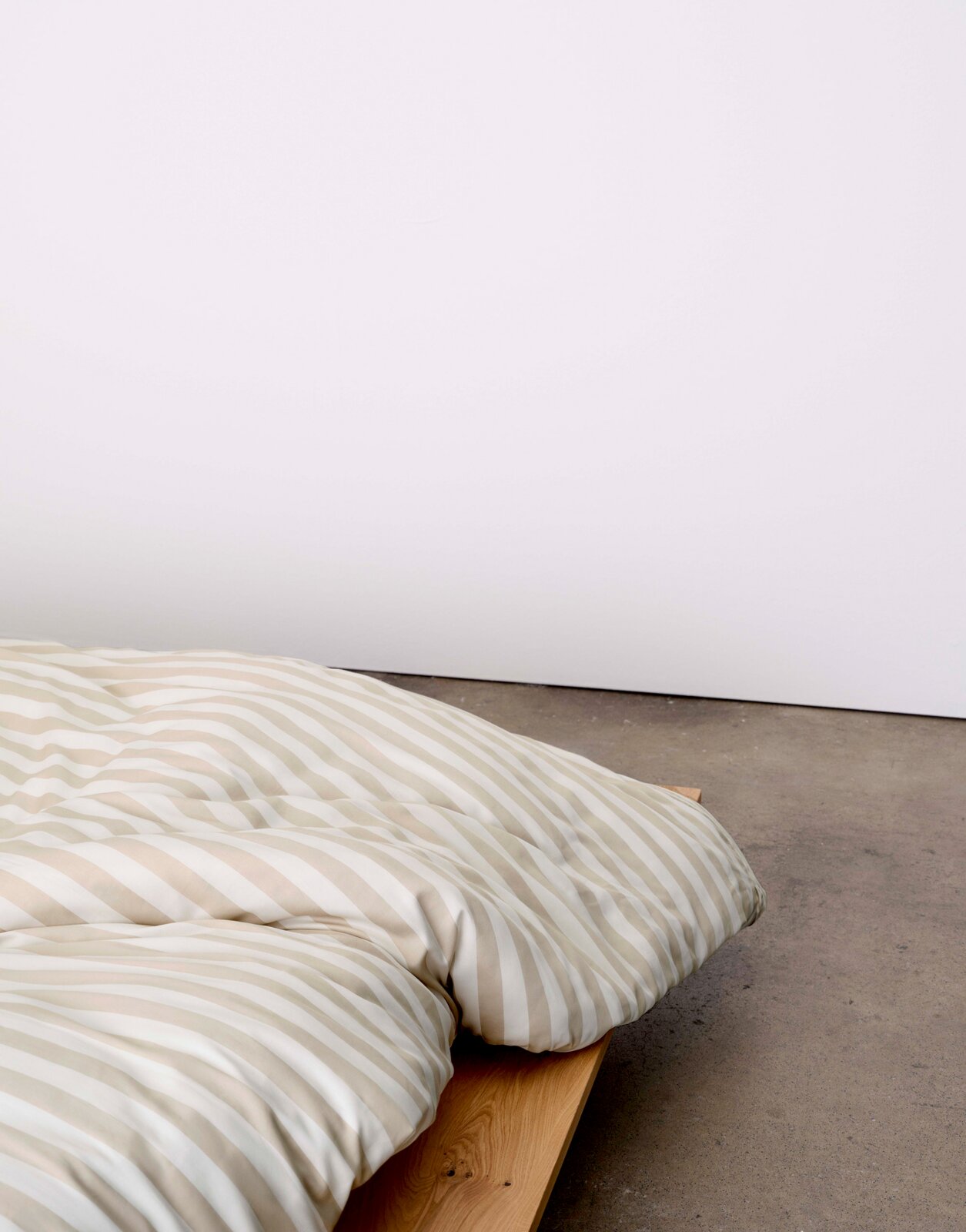 Bettwäsche mit beige-weißen Streifen auf einem Holzbett, seitliche Perspektive