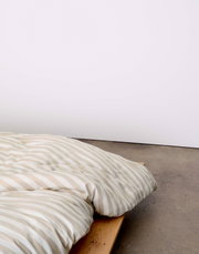 Bettwäsche mit beige-weißen Streifen auf einem Holzbett, seitliche Perspektive