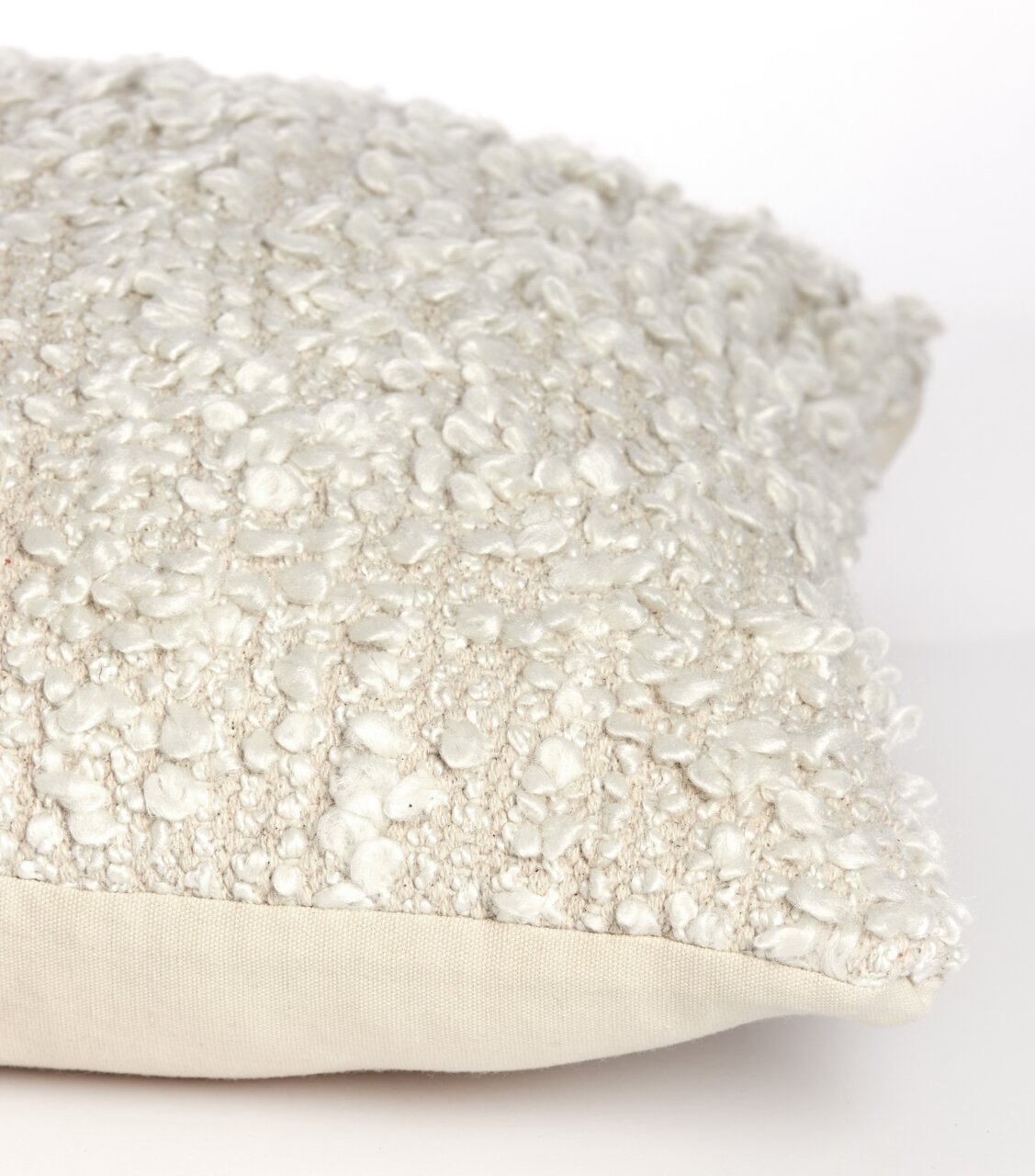 Nahaufnahme eines cremefarbenen Bouclé-Kissens in 45x45 cm Größe, seitliche Perspektive