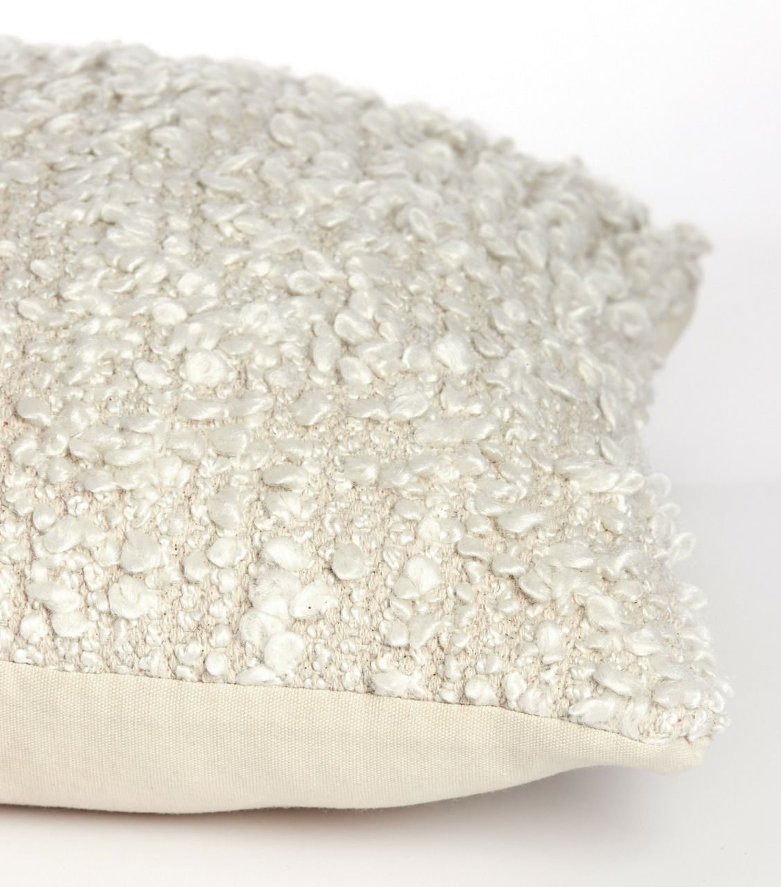 Nahaufnahme eines cremefarbenen Bouclé-Kissens in 45x45 cm Größe, seitliche Perspektive