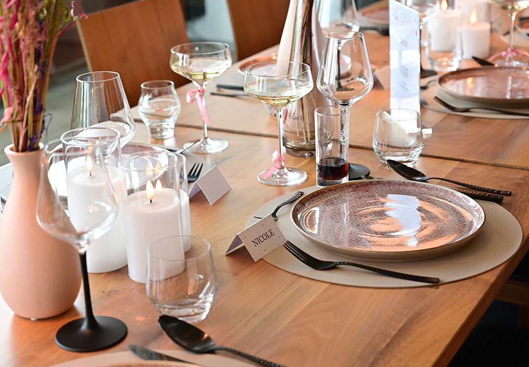 Een stijlvol gedekte eettafel met porseleinen servies, naamkaartjes, glazen en led-kaarsen
