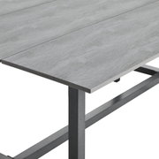 Close-up van een grijze tafel met metalen onderstel, vanuit een zijdelingse hoek gefotografeerd.