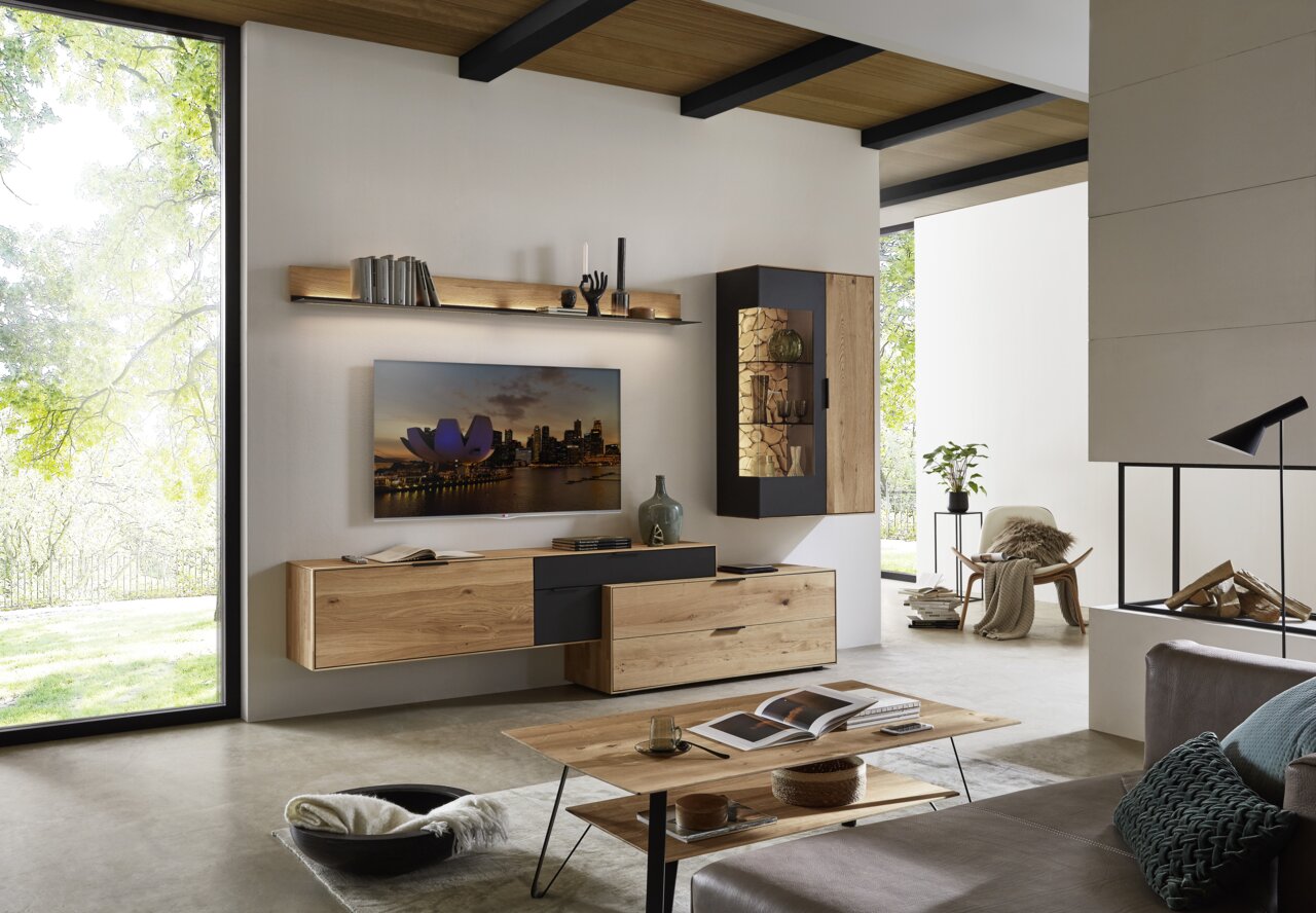 Moderne Wohnzimmer-Wandkombination aus Holz mit Hängeschränken, Regal und TV, seitliche Perspektive.