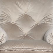 Nahaufnahme eines beigen Chefsessels mit Knopfheftung und weicher Polsterung, Vorderansicht