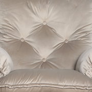 Nahaufnahme eines beigen Chefsessels mit Knopfheftung und weicher Polsterung, Vorderansicht