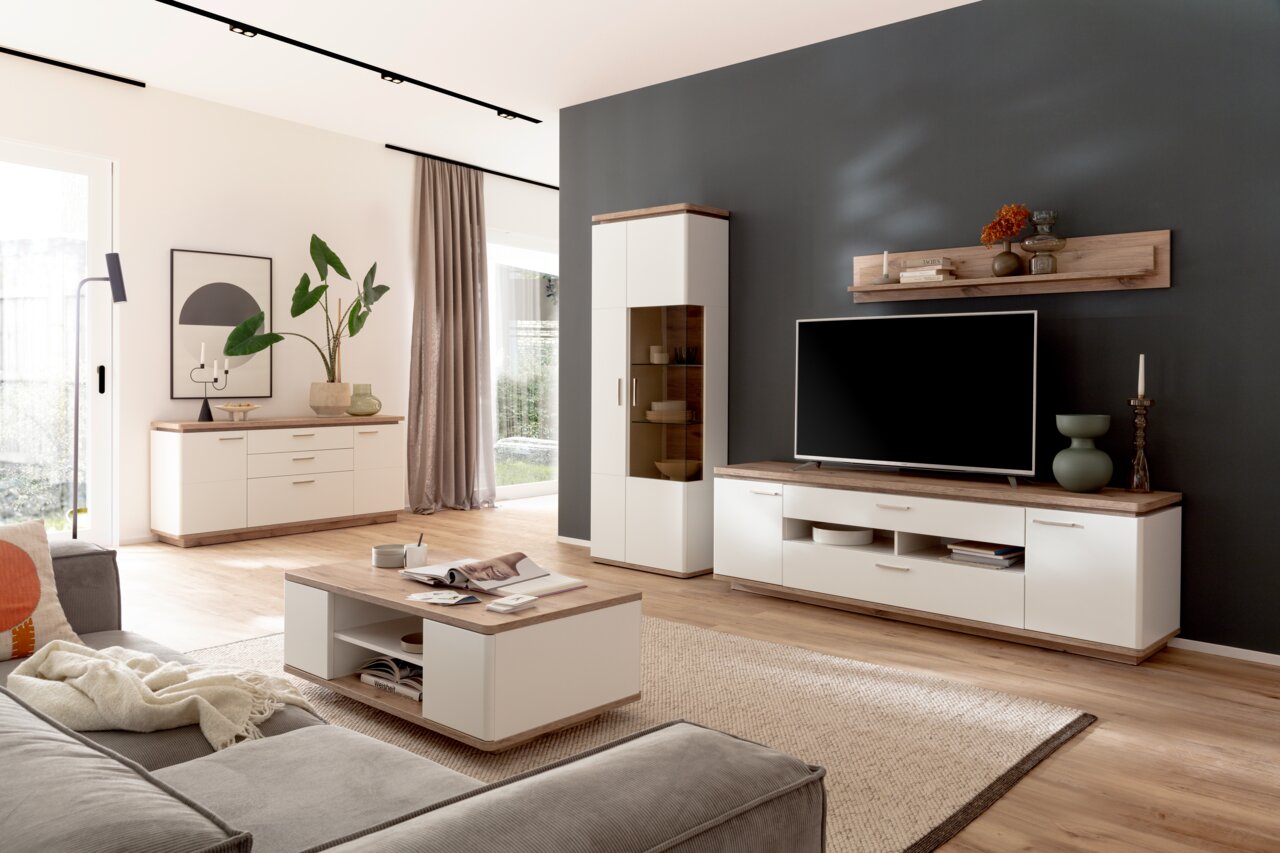 Modernes Wohnzimmer mit Zurbrüggen Wandboard PALERMO, TV-Schrank und Dekorationen, seitliche Perspektive.