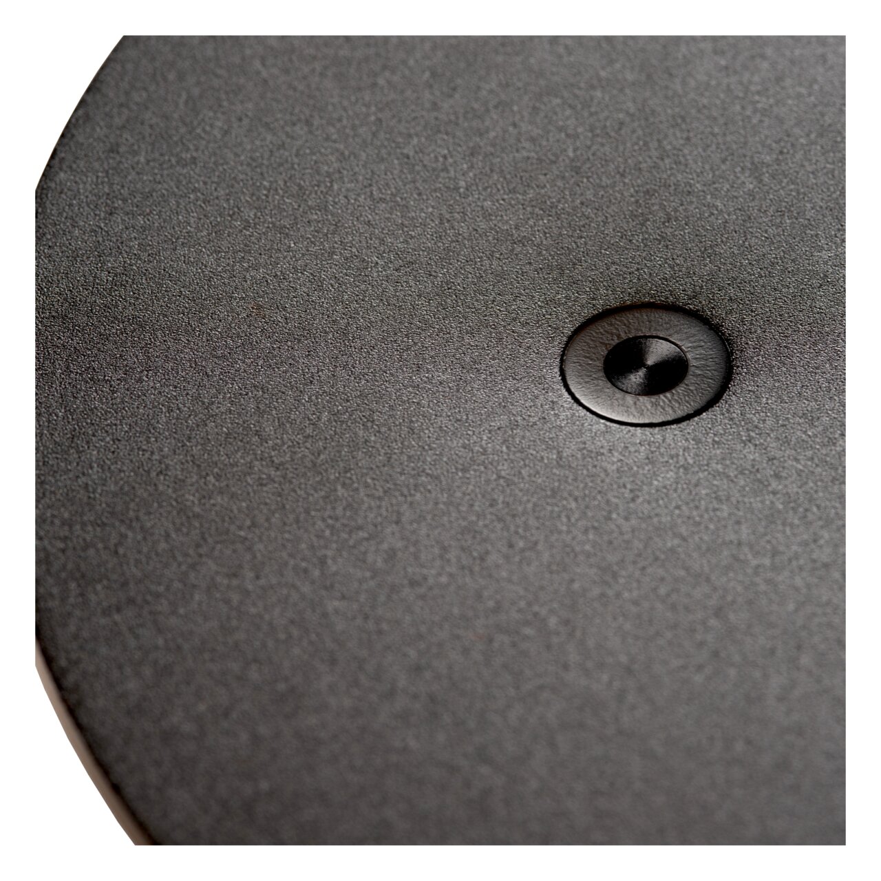 Nahaufnahme der Oberfläche einer Tisch- oder Schreibtischleuchte mit einem zentralen Knopf, von oben betrachtet.