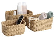 Dreiteiliges Aufbewahrungskorb-Set aus geflochtenem Material, gefüllt mit Pflegeprodukten und Handtüchern, aus seitlicher Perspektive fotografiert.