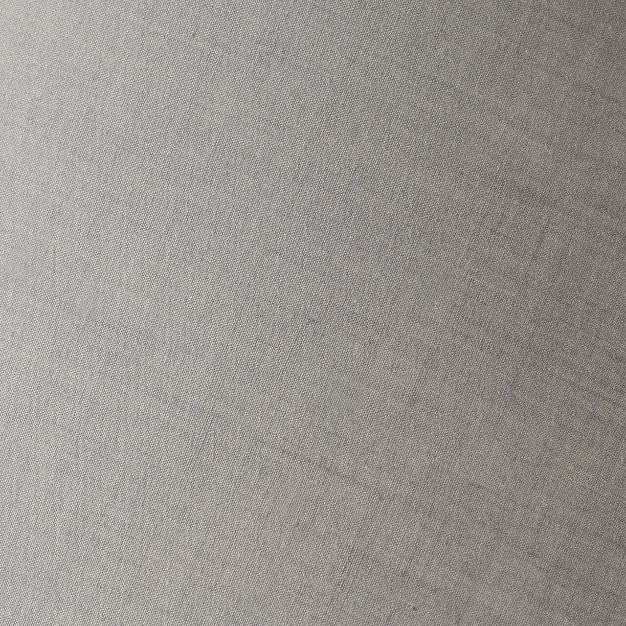 Nahaufnahme eines grauen Stoffes mit feiner Webstruktur, schräg fotografiert.