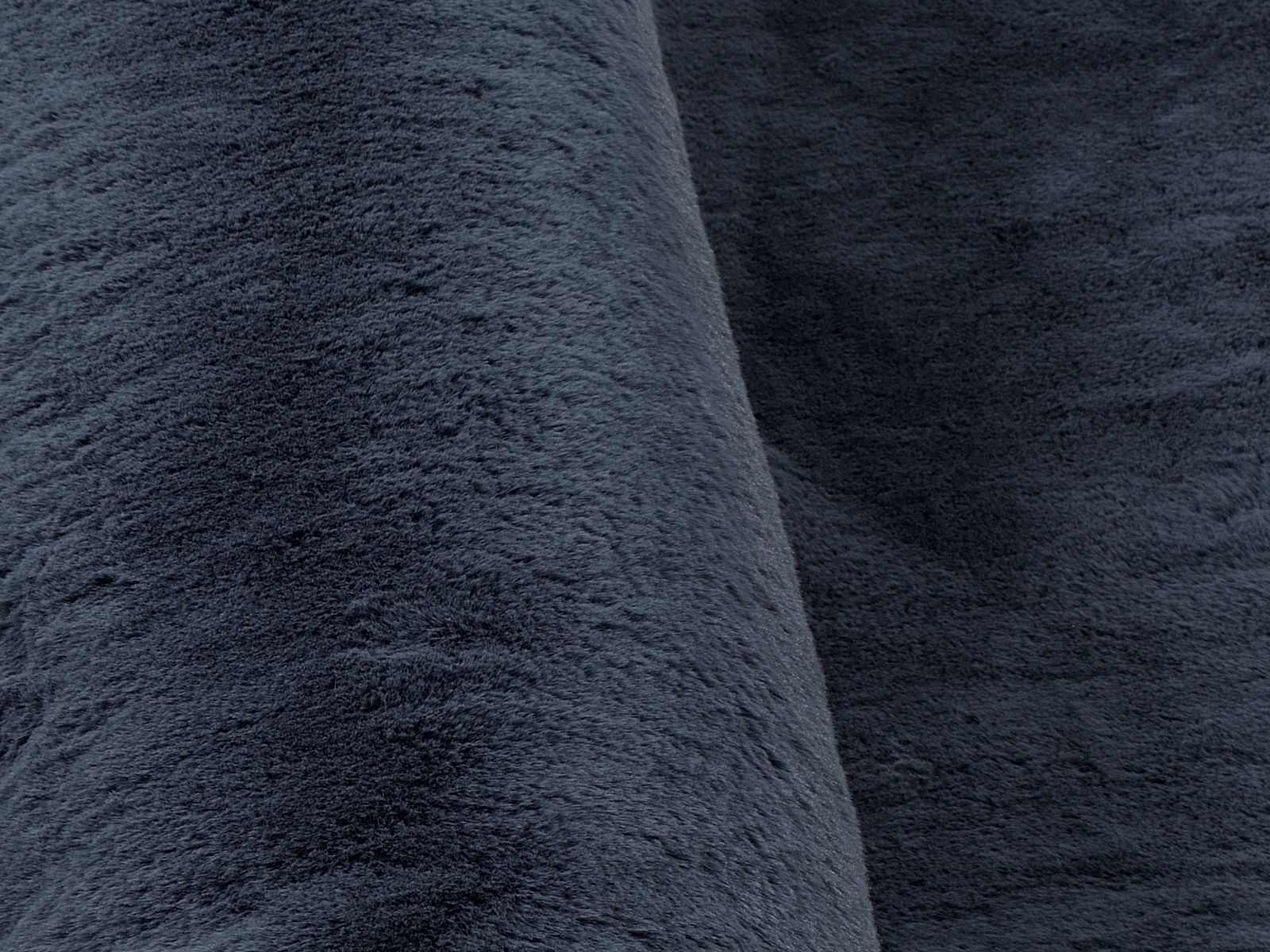 Nahaufnahme eines dunkelgrauen Fellteppichs mit weicher, flauschiger Textur.
