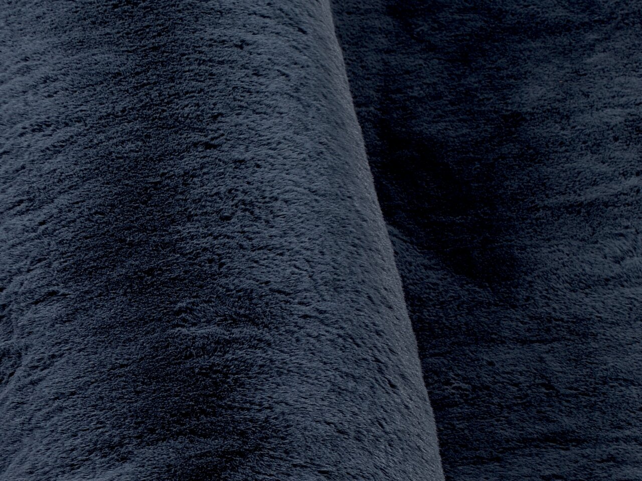 Nahaufnahme eines dunkelgrauen Fellteppichs mit weicher, flauschiger Textur.