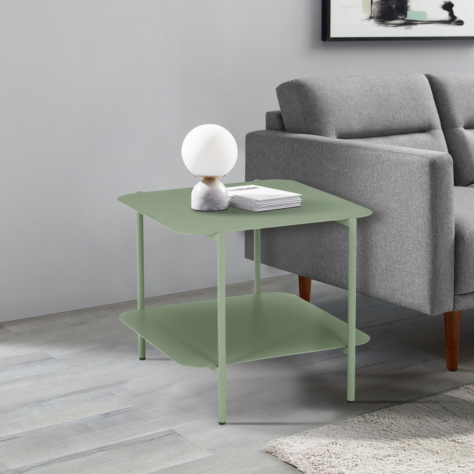 Moderner grüner Beistelltisch mit zwei Ebenen, seitliche Perspektive, neben einem grauen Sofa platziert.