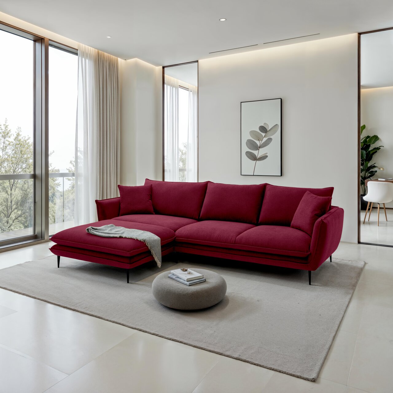 Een bordeauxrode, moderne L-vormige hoekbank met een chaise longue aan de linkerkant, zwarte metalen poten en bijpassende kussens in een lichte woonkamer perspectief: 3/4-vooraanzicht vanuit een lichte hoek links.
