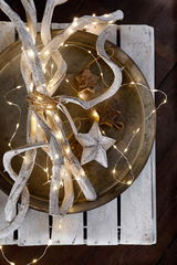 Draufsicht auf eine dekorative Anordnung mit LED-Lichterkette, weißen Ästen und einem Stern auf einem Tablett.