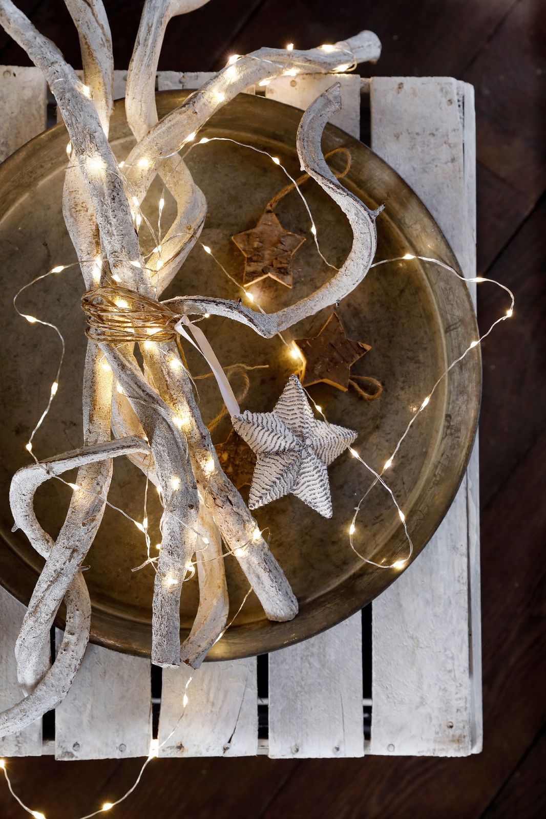 Draufsicht auf eine dekorative Anordnung mit LED-Lichterkette, weißen Ästen und einem Stern auf einem Tablett.