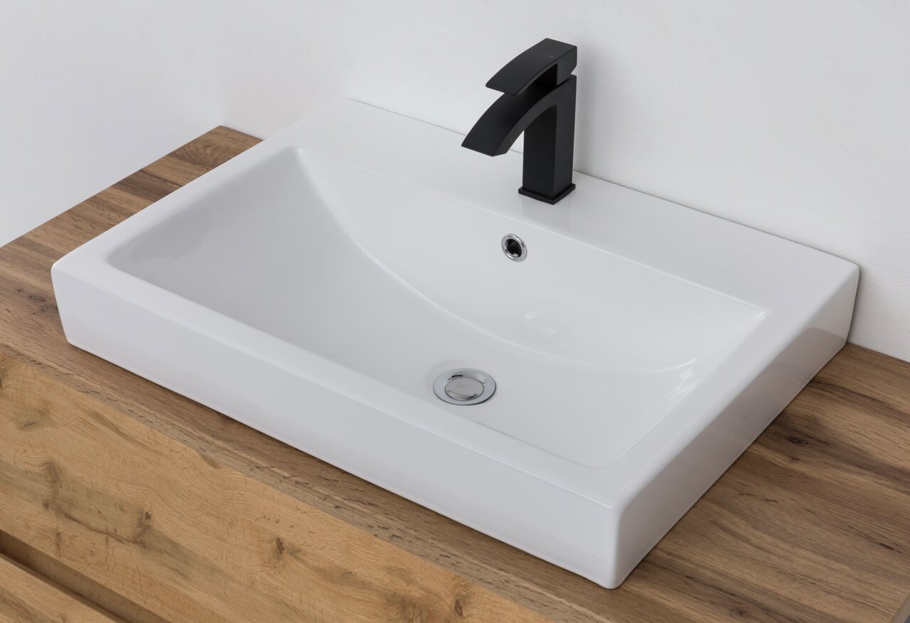 Moderner Waschtisch mit rechteckigem, weißem Becken und schwarzem Wasserhahn, aus der Vogelperspektive auf einer Holzoberfläche.