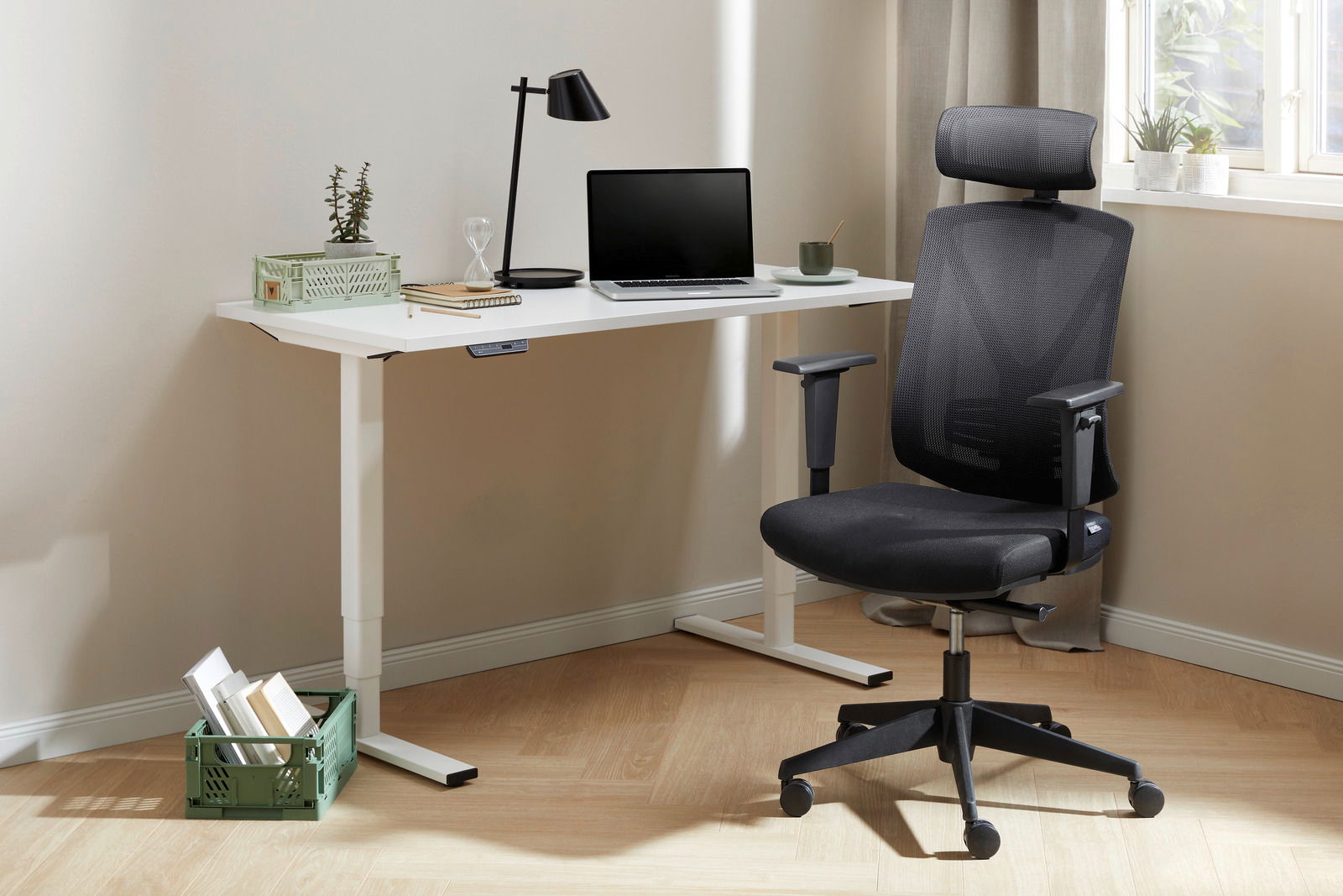Moderner E-Schreibtisch mit weißer Tischplatte und höhenverstellbaren Beinen, ausgestattet mit einem Laptop, einer Lampe und Pflanzen, aus seitlicher Perspektive fotografiert.