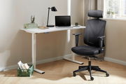 Moderner E-Schreibtisch mit weißer Tischplatte und höhenverstellbaren Beinen, ausgestattet mit einem Laptop, einer Lampe und Pflanzen, aus seitlicher Perspektive fotografiert.